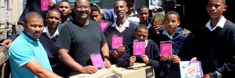 Die enorme vrag boeke wat deur Jack Doyle van Engeland per vragskip na Gansbaai Primêr gestuur is, met Tommy Volkwyn (skoolhoof) direk agter een van die kartondose